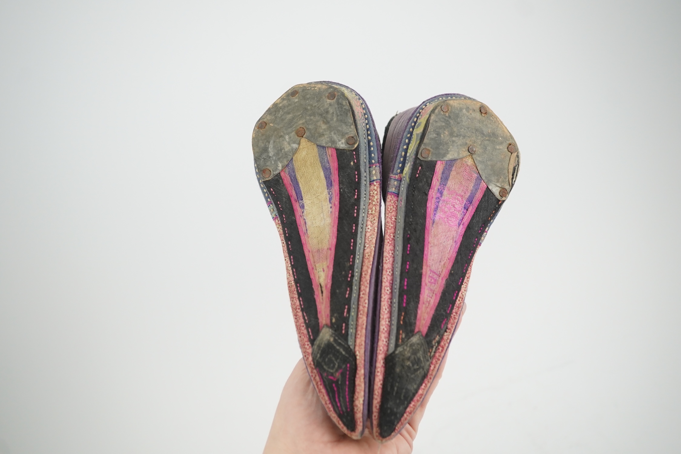 Four pairs of late 19th / early 20th Chinese ladies bound foot shoes, made in various coloured silks, with colourful floral embroidered motifs, two pairs with decorative silk pom-poms and another made of purple and black